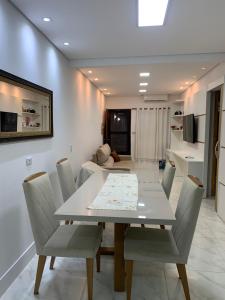 a dining room with a white table and chairs at Casa com churrasqueira Guilhermina Praia Grande in Praia Grande