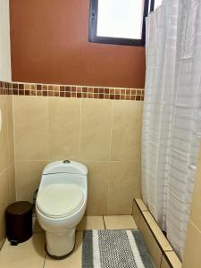 a bathroom with a white toilet and a window at Amplio Apartamento, en Colonia Cerezos, Tercer nivel in Quetzaltenango