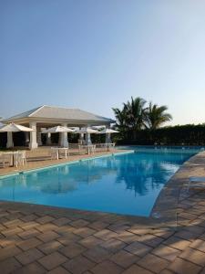 a large swimming pool with chairs and umbrellas at Casa en Playa Privada - A pocos minutos de General Villamil Playas in Posorja