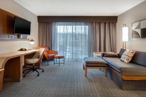 a hotel room with a couch and a desk with a computer at Courtyard by Marriott State College in State College