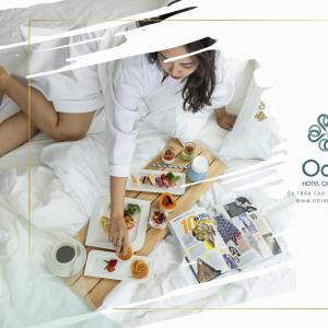 a woman laying in bed with a tray of food at Odin Hotel Quy Nhon in Quy Nhon