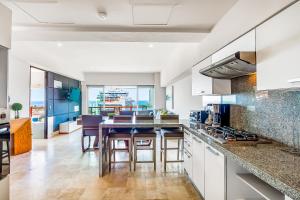 a kitchen with white cabinets and a table with stools at Deck 12 - 807 in Puerto Vallarta