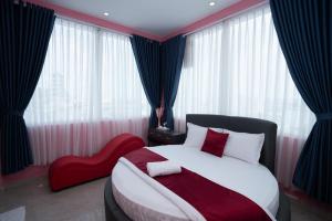 - une chambre avec un grand lit et une chaise rouge dans l'établissement EROS HOTEL, à Hô-Chi-Minh-Ville