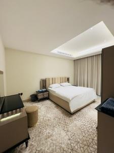 una camera da letto con un grande letto bianco e una televisione di REMAZ ROSE BOULEVARD a Riyad