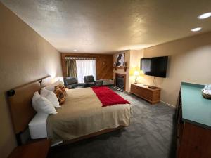 ein Hotelzimmer mit einem großen Bett und einem TV in der Unterkunft Whitetail Lodge in Saint Germain