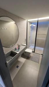een badkamer met een wastafel, een toilet en een spiegel bij AsuaCasaNaBarra - Barra de São Miguel - Casa de Praia in Barra de São Miguel