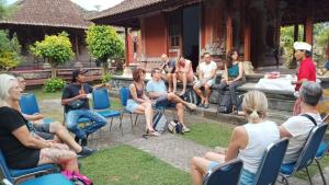 a group of people sitting in chairs in front of a house at Pinge Traditional Village in Petang