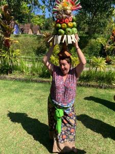 a man carrying a tray of fruit on his head at Pinge Traditional Village in Petang