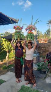 two women are holding up a bunch of bananas on their heads at Pinge Traditional Village in Petang