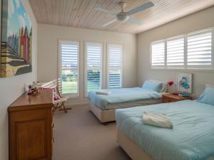 a bedroom with two beds and a ceiling fan at 'South Pacific' - Luxury Oceanfront at Culburra! in Culburra Beach