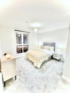 een witte slaapkamer met een bed en 2 ramen bij City Escape - Unwind in Style in Barking