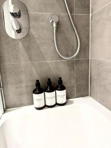 tre bottiglie sedute su un bancone in una doccia di City Escape - Unwind in Style a Barking