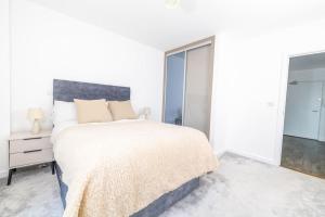 a white bedroom with a large bed and a mirror at City Escape - Unwind in Style in Barking