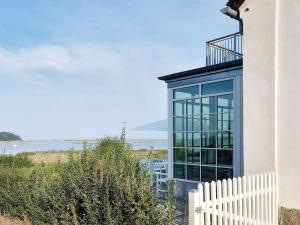 une maison en verre avec une clôture blanche et l'océan dans l'établissement Holiday home Assens IV, à Assens