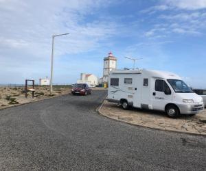a white camper van parked in front of a lighthouse at Sempre pronta para férias in Amadora