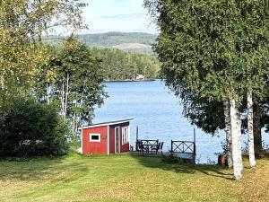 a small red shed on the side of a lake at Holiday home TRÖNÖDAL in Vallsta