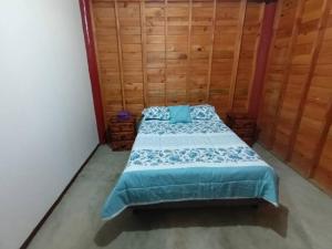 1 dormitorio con 1 cama en una habitación con paredes de madera en Cabaña de Madera, El Pochote, en San Andrés Huayapan