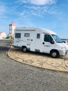 a white camper van parked in front of a lighthouse at Sempre pronta para férias in Amadora