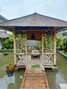 a wooden gazebo with a table on the water at Nanita Homestay in Talun
