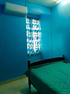 ein blaues Schlafzimmer mit einem Bett und einem Fenster in der Unterkunft MJ homestay in Nibung Tebal