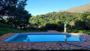 a swimming pool in the middle of a field with a mountain at Sítio Bárbara in Brumadinho