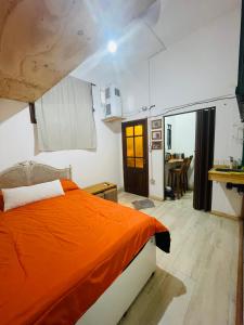 1 dormitorio con cama de color naranja y comedor en Rinconcito en Pompeya en Buenos Aires