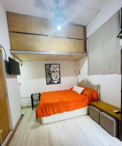 1 dormitorio con 1 cama con colcha de color naranja en Rinconcito en Pompeya en Buenos Aires