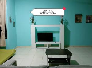 ein Wohnzimmer mit einem TV und einer blauen Wand in der Unterkunft MJ homestay in Nibung Tebal