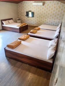Zimmer mit 3 Betten in einem Zimmer mit Holzböden in der Unterkunft Mysticstays Resort in Wai