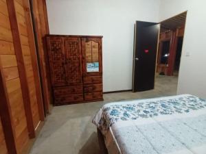 een slaapkamer met een bed en een houten kast bij Cabaña de Madera, El Pochote in San Andrés Huayapan