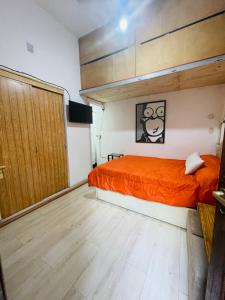 1 dormitorio con cama de color naranja y puerta de madera en Rinconcito en Pompeya en Buenos Aires