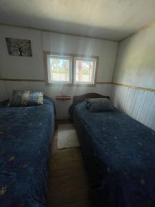 duas camas num pequeno quarto com duas janelas em Cabaña EL VIEJO SAM em Curaco de Velez