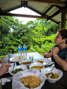 a group of people sitting at a table with food at Rainforest cabin in Deniyaya