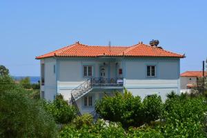 ein weißes Haus mit rotem Dach in der Unterkunft Troumpas Family Rooms & Apartments in Leonidi