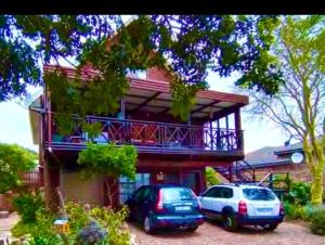 two cars parked in front of a house with a balcony at Coastal Cottage in Klein Brak Rivier