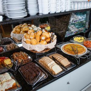 um buffet repleto de diferentes tipos de pão e pastelaria em OK Inn Hotel em Tubarão