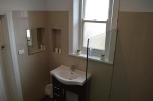 een badkamer met een wastafel, een spiegel en een raam bij Two Cow Cottage Bed & Breakfast in Keith