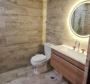 a bathroom with a toilet and a sink and a mirror at Departamento moderno a 2 cuadras del mar in Mar Azul