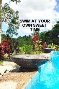 a water fountain next to a swimming pool with the words swim at your own sweet at Captain's Cabin Resort - Naval Heritage (Swimming Pool) in Kota Bharu