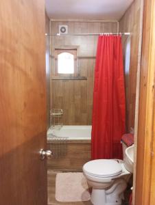 a bathroom with a red shower curtain and a toilet at Cabañas Cauchao Chaitén in Chaitén
