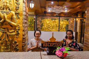 two women standing in a room with a sign that says reception at Diva Patong Hotel in Patong Beach