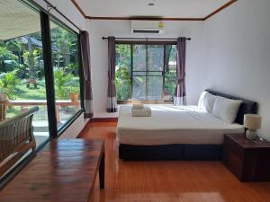 a bedroom with a bed and a large window at Baan Long Beach in Ko Lanta