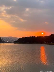 a sunset over a large body of water with trees at Anh Trang Homestay in Da Lat