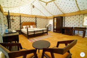 a bedroom with a bed and a table and chairs at Sam Sand Dunes Desert Safari Camp in Jaisalmer