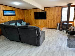 a living room with a black couch and a television at Rustic Retreat Esperance in Esperance