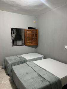 Habitación con 2 camas y espejo en la pared. en Cantinho da paz, en Marechal Deodoro