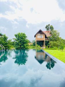 una piscina de agua frente a una casa en Prana Ayurveda Chalet- Sigiriya en Sigiriya