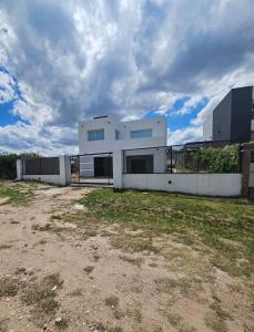 una casa blanca con una valla en un patio en CountryHome Tierra Alta, en Villa San Nicolás