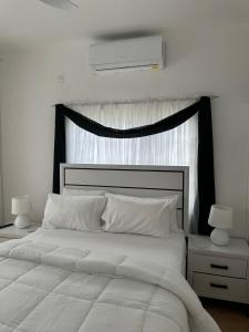 a bedroom with a large white bed with a black headboard at Eagles Nest Villa House AC TV WIFI Fan Luxury Modern in Albion