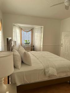 ein weißes Bett mit weißen Kissen im Schlafzimmer in der Unterkunft Eagles Nest Villa House AC TV WIFI Fan Luxury Modern in Albion